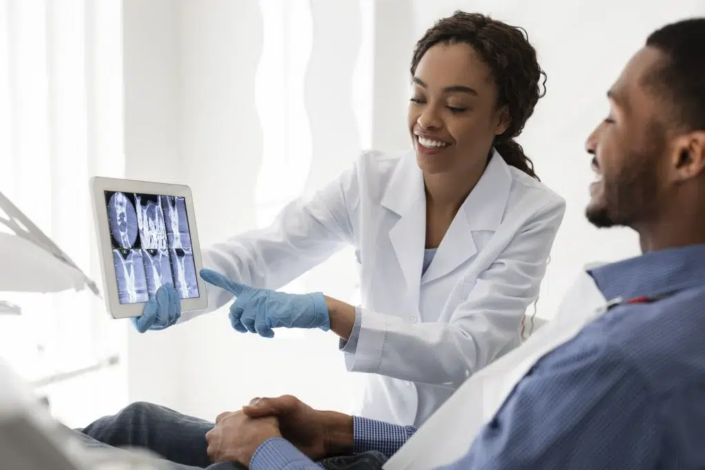 Smiling African Female Dentist Showing Patient Teeth Xray